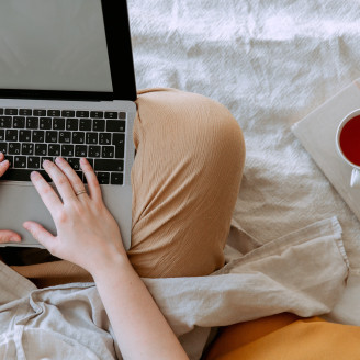 crop person using laptop with empty screen in bed near cup 3975580
