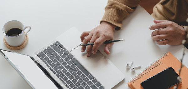 person holding black pen while using laptop 3787317